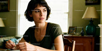 Thoughtful woman sitting at table in warm home interior