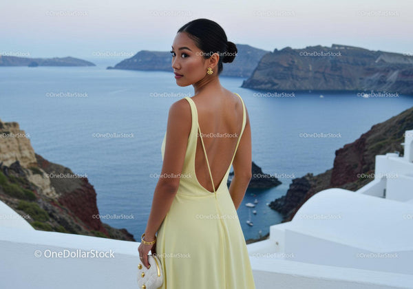 Elegant woman in yellow dress overlooking sea cliffs