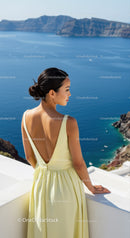 Woman in yellow dress overlooking serene ocean cliffs