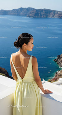 Woman in yellow dress overlooking serene ocean cliffs