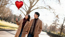 Couple holding hands with heart balloon in autumn park