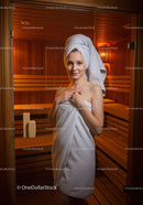 Young Woman Relaxing in Sauna with Towel Wrapped Around Body