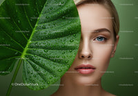Close-Up of Woman with Blue Eyes Behind Large Green Leaf with Dew Drops