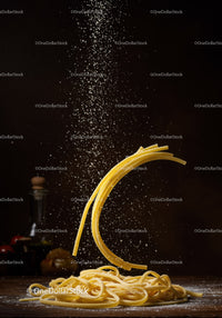 Falling flour dust over fresh Italian pasta on wooden table