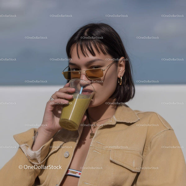 Młoda kobieta pijąca żółte smoothie w casualowym letnim stroju
