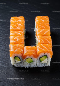 Fresh salmon and avocado sushi rolls on black slate
