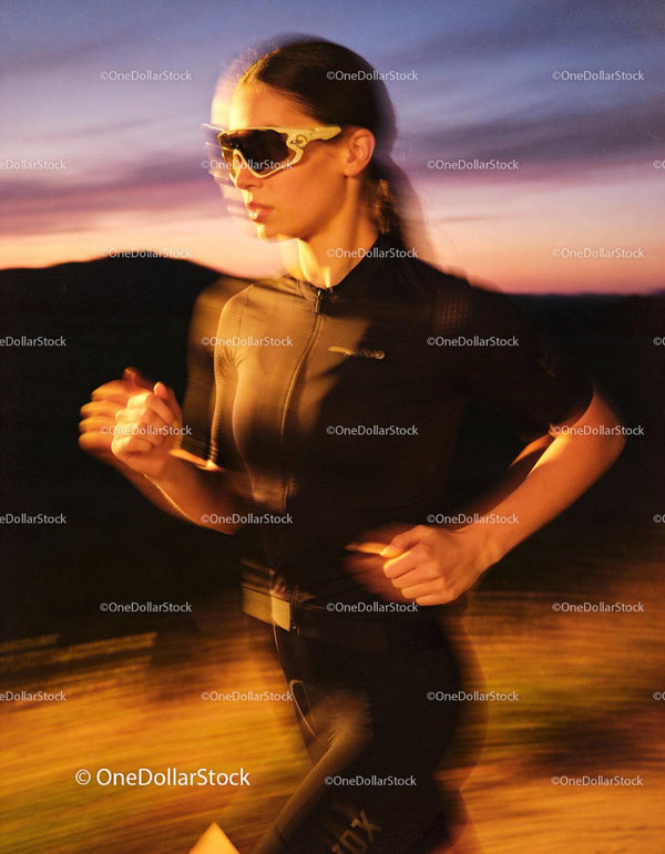 Focused female runner training outdoors at sunset