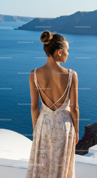Woman in floral dress overlooking calm sea coast