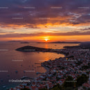 Vibrant Sunset Over A Small Coastal Town With Boats and Red Roofs