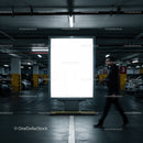 Person walking past illuminated billboard in parking garage