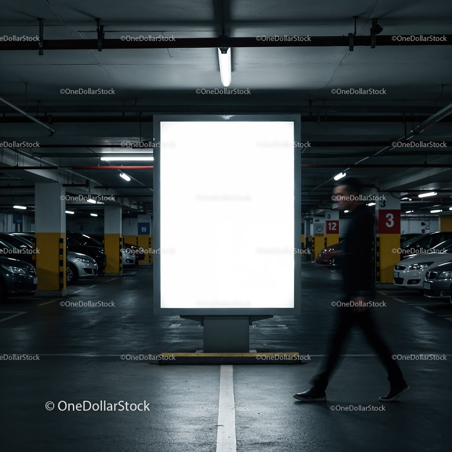 Person walking past illuminated billboard in parking garage