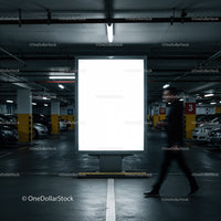 Person walking past illuminated billboard in parking garage