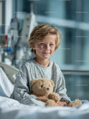 Smiling Boy with Teddy Bear Sitting in Hospital Bed