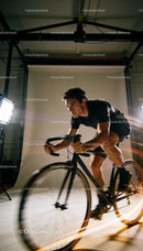 Focused man riding racing bike indoors in motion
