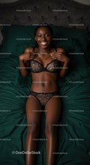 Smiling woman relaxing on bed in elegant lingerie set