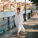 Woman in flowing white dress walking by lake promenade
