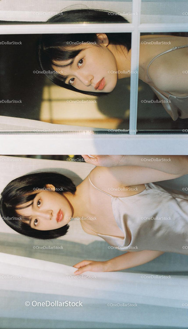 Young woman reflected in window wearing silk slip dress
