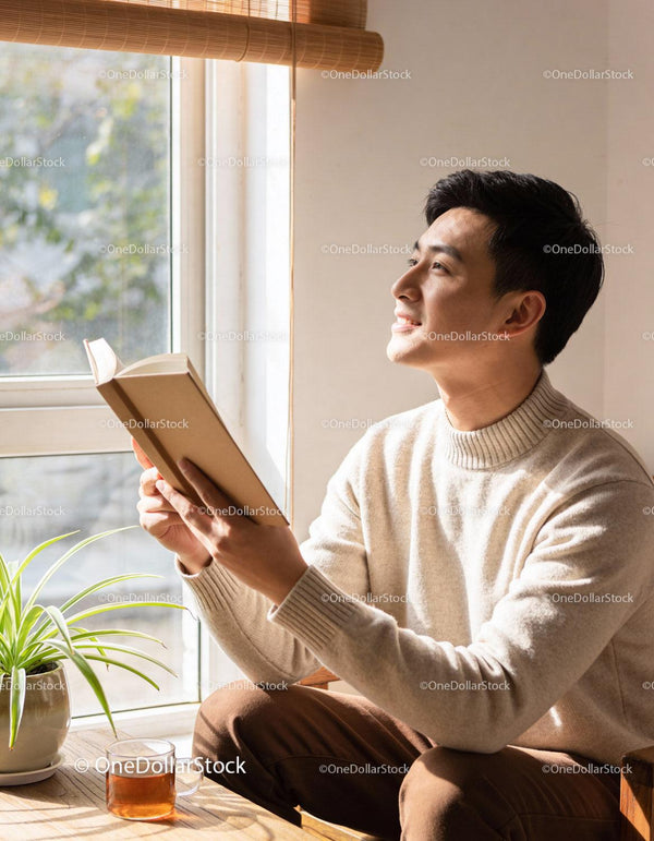 Man enjoying quiet moment reading book by window