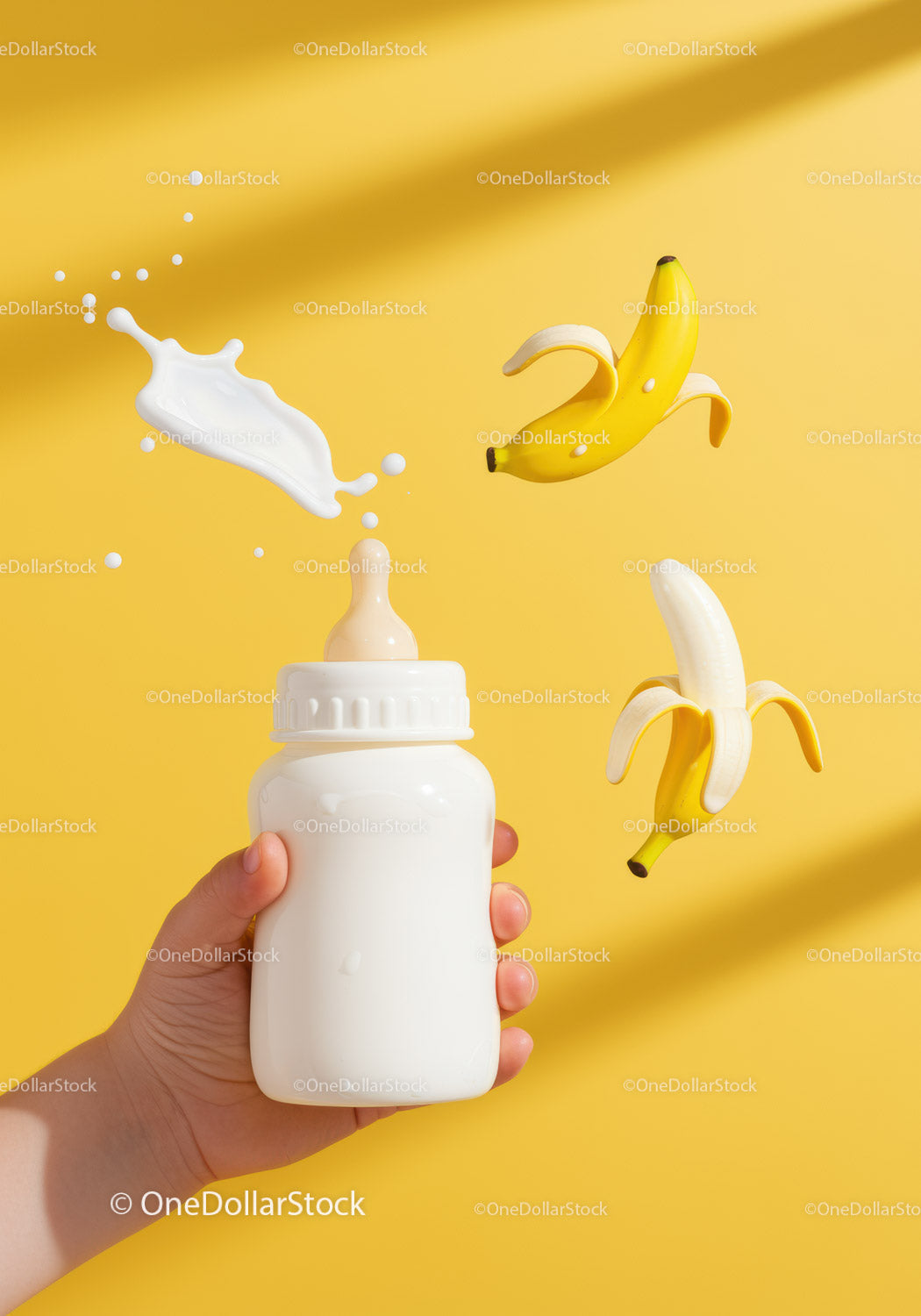 Ręka trzymająca butelkę dla dziecka z pluskiem i bananami
