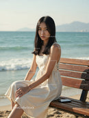 Elegant Woman in White Dress Sitting by Relaxing Seaside Landscape