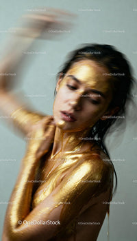 Woman with flowing gold body paint in abstract motion