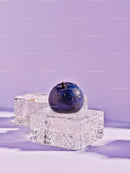 Fresh blueberry on clear ice cubes with purple background