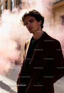 Young man in brown coat surrounded by soft smoke