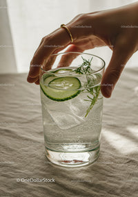 Hand Reaching for Refreshing Cucumber and Herb Sparkling Water