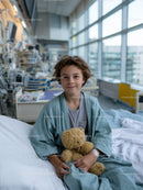 Young boy with teddy bear in hospital room at modern medical facility