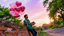 Man Holding Heart Balloons and Chocolates at Sunset
