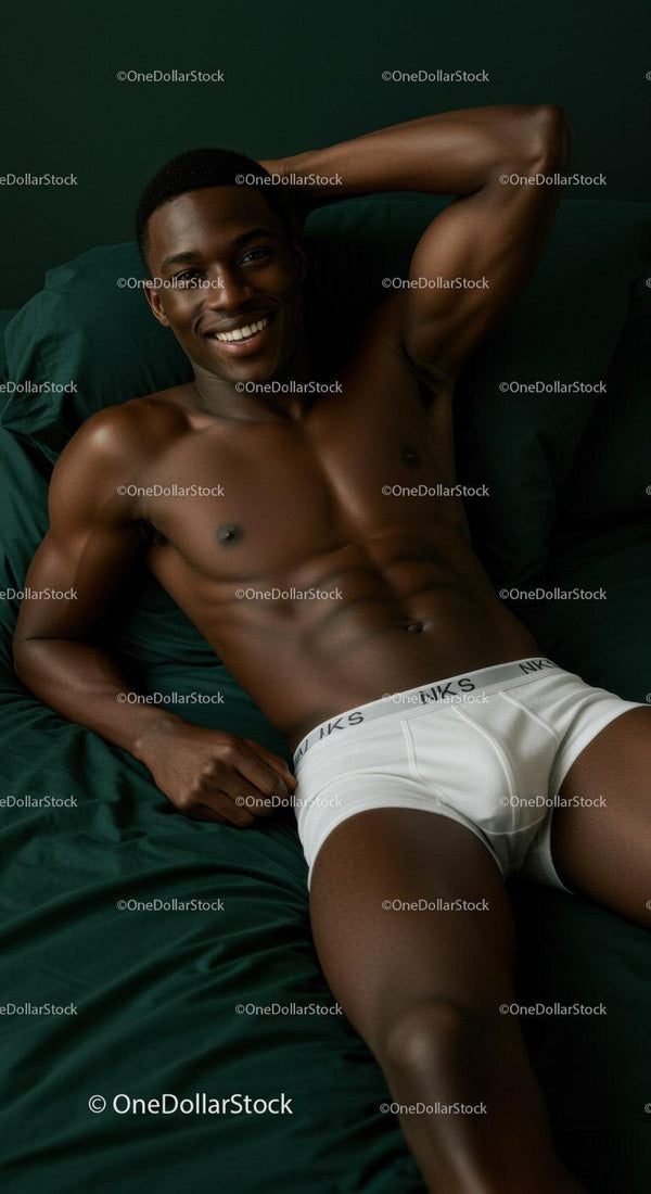 Smiling man relaxing on dark green bedding in underwear
