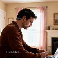 Focused young man working on laptop in cozy home