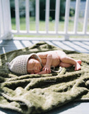 Newborn baby sleeping peacefully on soft green blanket