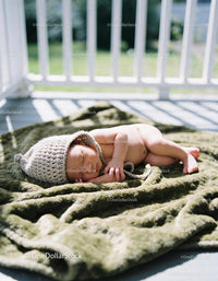Newborn baby sleeping peacefully on soft green blanket