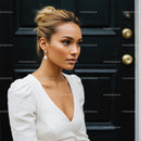 Elegant woman in white dress posing by black door