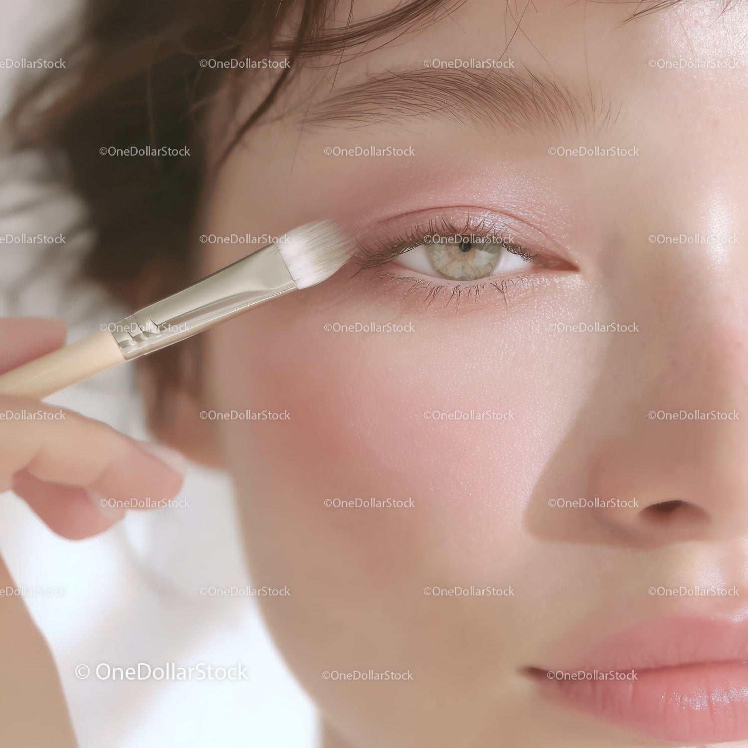 Close-up of woman applying eye makeup with a brush in soft lighting
