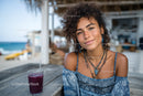 Young Woman Relaxing with Juice at Beachside Cafe During Summer