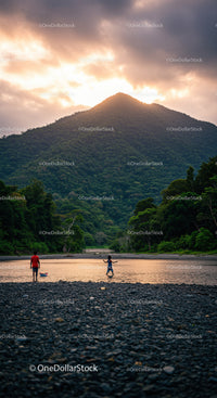Scenic Mountain Landscape with Children Playing by River During Sunset