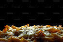 Delicious cheesy pasta dish with herbs on black background