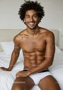Happy young man relaxing on bed in comfortable underwear