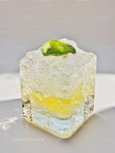 Close up of clear ice cube with lemon and mint leaf