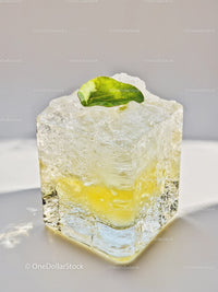 Close up of clear ice cube with lemon and mint leaf