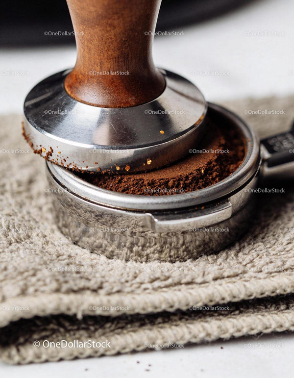 Close up of coffee tamper pressing ground espresso