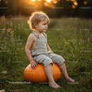 Toddler Sitting on Large Pumpkin in Autumn Field