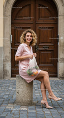 Smiling woman in pink dress sitting with fresh groceries
