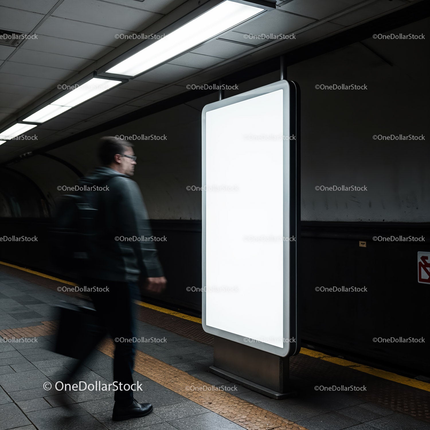 Mężczyzna przechodzący obok pustej, oświetlonej tablicy reklamowej pod ziemią