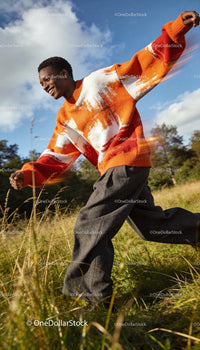 Joyful man in vibrant sweater running through meadow