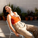 Carefree young woman laughing in sunny urban garden
