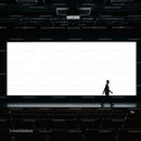 Silhouette of man walking in empty theater with bright screen