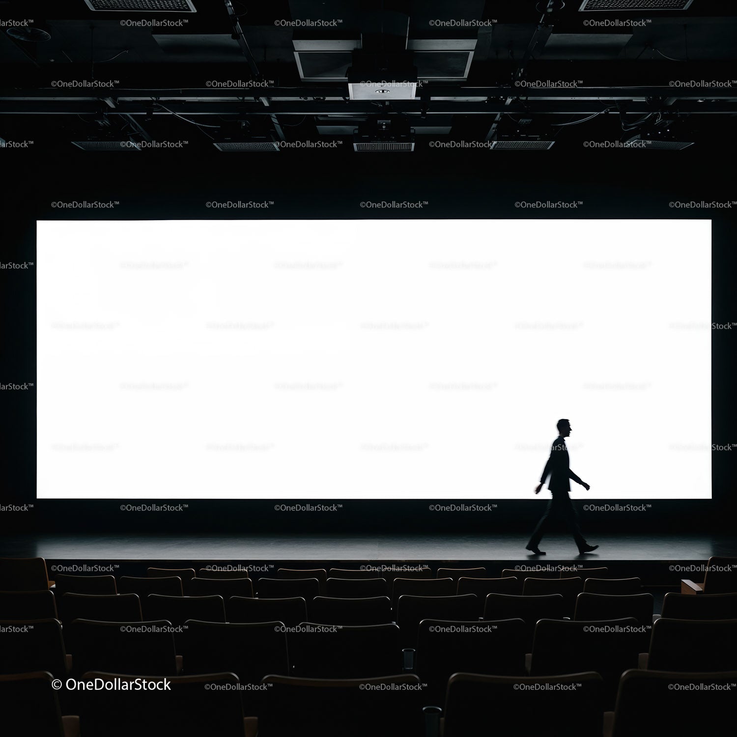Silhouette of man walking in empty theater with bright screen